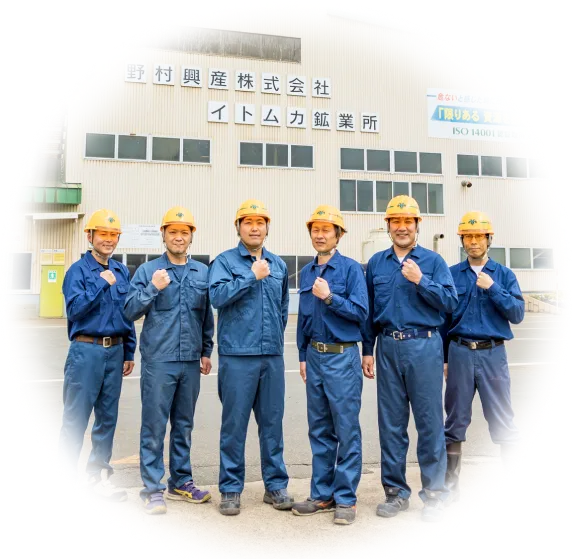 社屋の前でガッツポーズをとる男性従業員6名